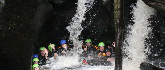 group of people in water at the bottom of a canyon on a canyoning experience in scotland