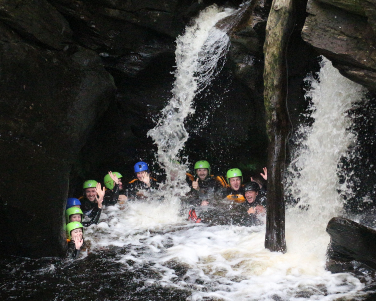 group of people in water at the bottom of a canyon on a canyoning experience in scotland