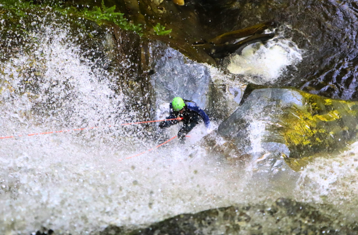 person abseiling down into a canyon on a canyoning experience in scotland