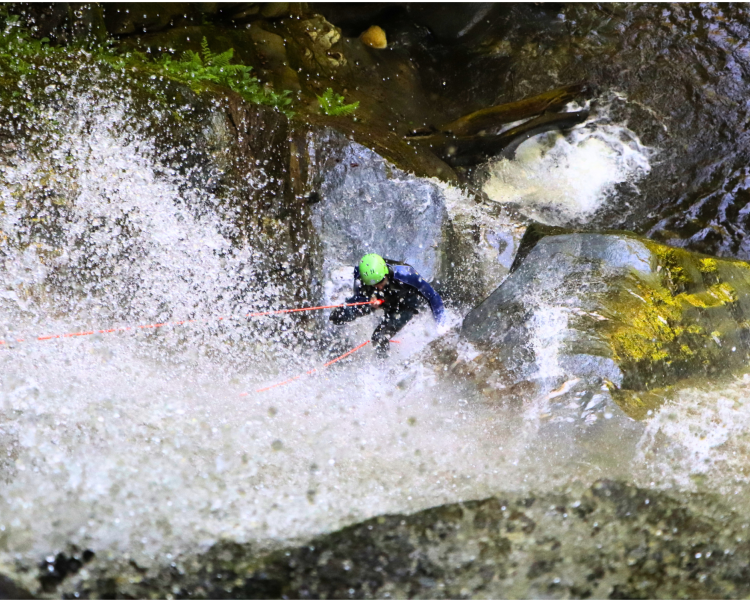 person abseiling down into a canyon on a canyoning experience in scotland