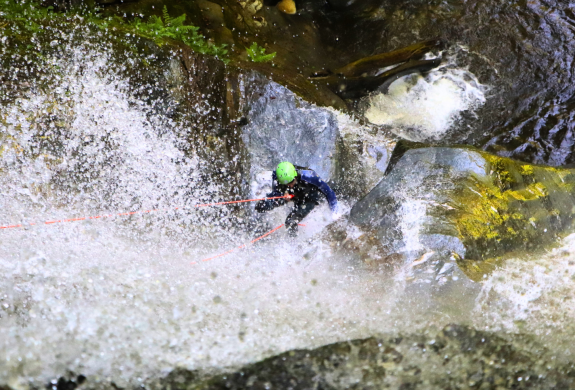 person abseiling down into a canyon on a canyoning experience in scotland