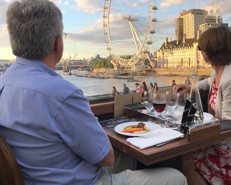 a couple enjoying a meal looking out the window at the london eye on board the bustronome london bus