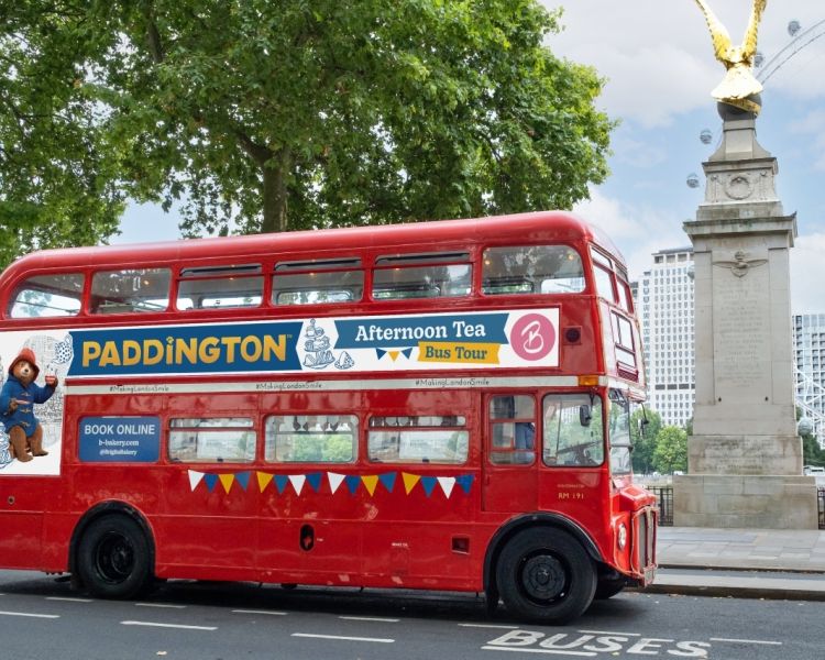 the red double decker paddington afternoon tea tour bus driving through london
