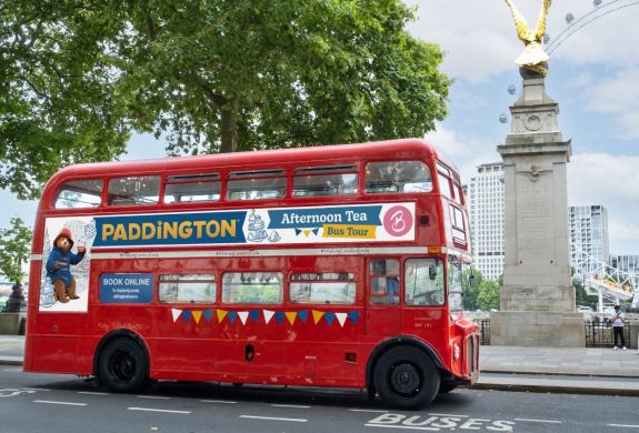 the red double decker paddington afternoon tea tour bus driving through london