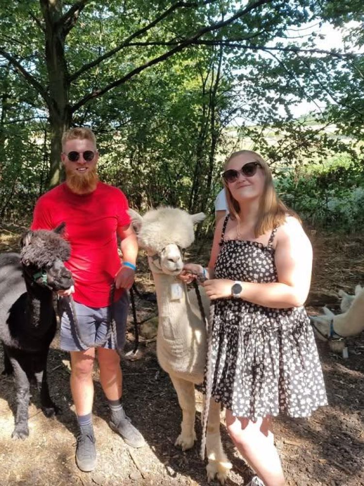 man and a woman standing next to alpacas on an alpaca walk experience