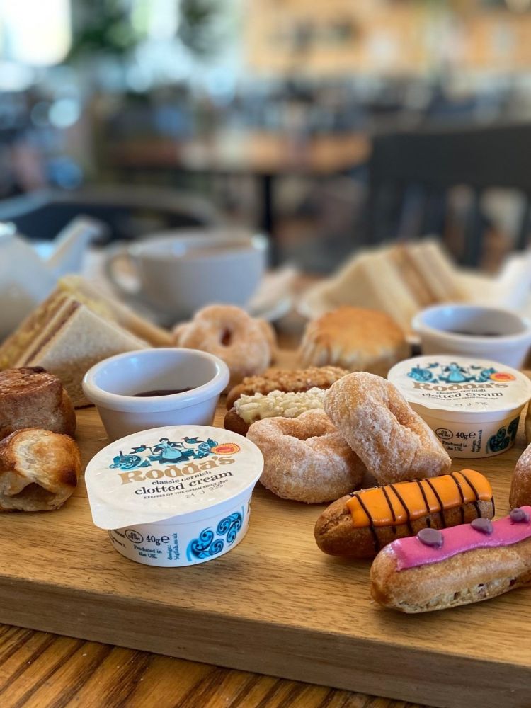 an afternoon tea spread with sandwiches, cakes and scones and pot of tea