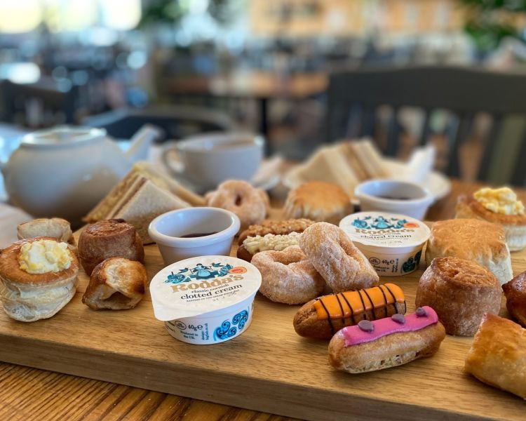 an afternoon tea spread with sandwiches, cakes and scones and pot of tea