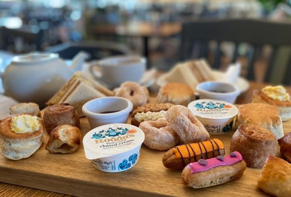 an afternoon tea spread with sandwiches, cakes and scones and pot of tea