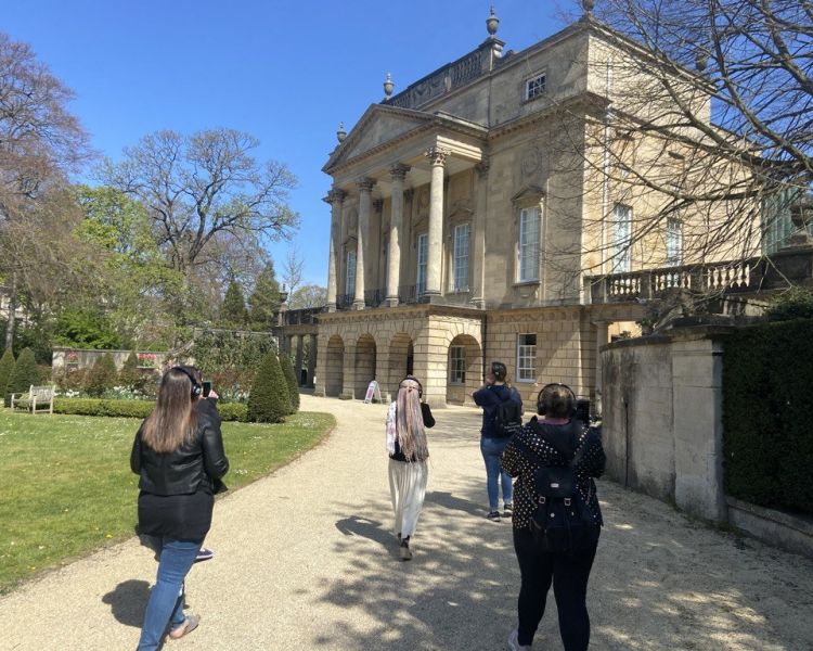 Girls walking up the driveway of a grand house in bath on a bridgerton walking tour
