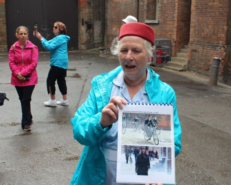 Midwife tour guide holding photos from the show on a call the midwife locations tour