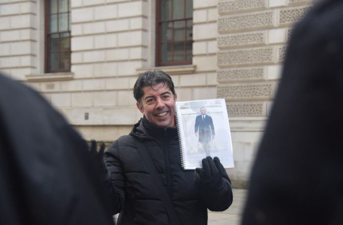 Guide holding photo of movie scene seen on a spy movie film locations walking tour in london