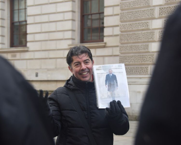 Guide holding photo of movie scene seen on a spy movie film locations walking tour in london