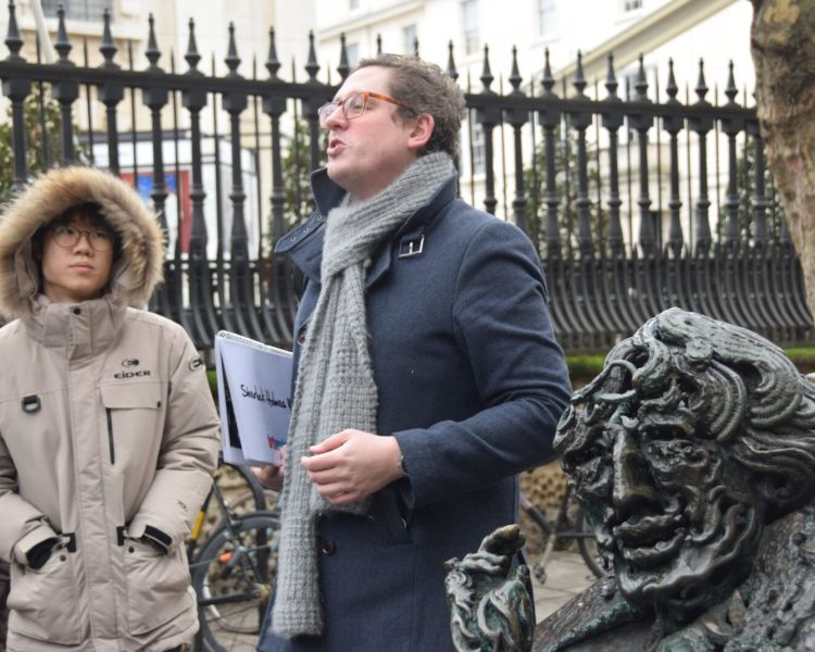 Guide talking to group next to the oscar wilde memorial seen on a sherlock holmes walking tour in london