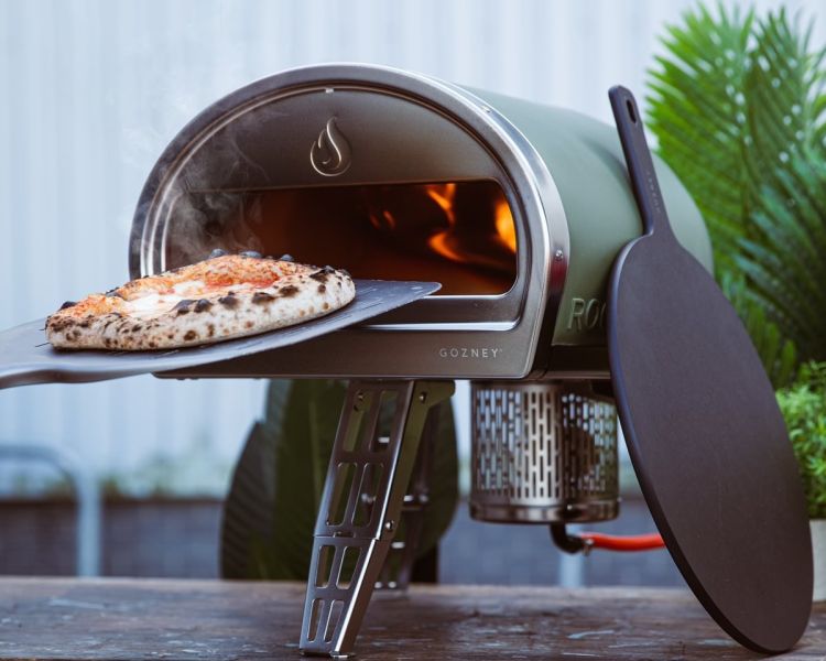 pizza going into an outdoor pizza oven on a pizza making class