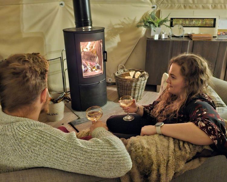 Couple sat inside tree dome by log fire