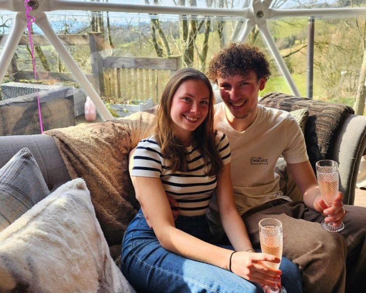 Couple sat on sofa inside tree dome
