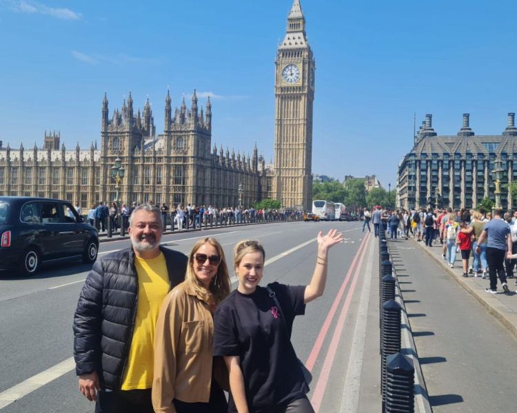 Three people posing for photo in front of big ben on a tour of london