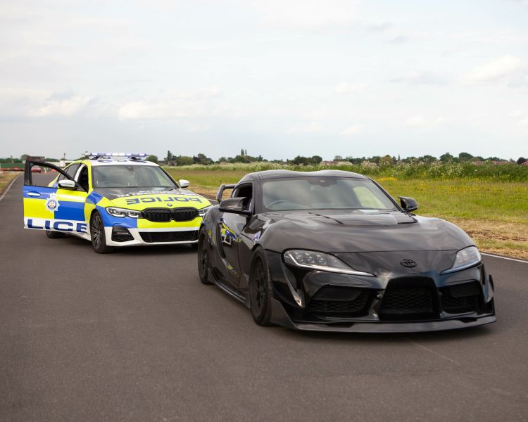 a police interceptor bmw behind a black sports car on a race track as part of a police interception driving experience
