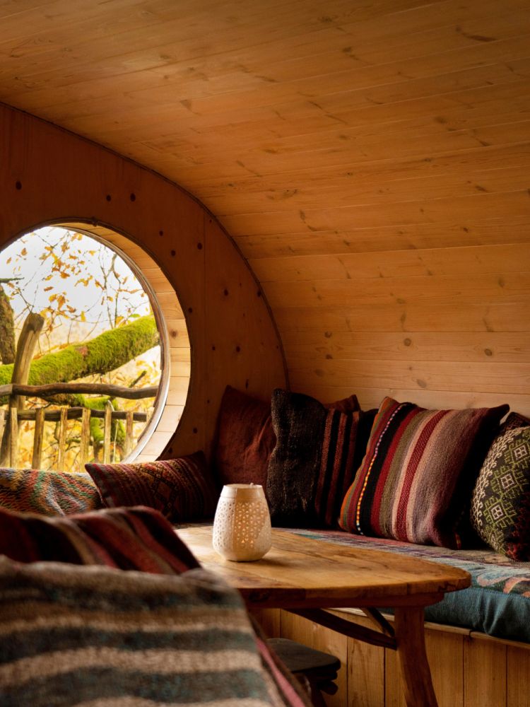 the living area with comfy seating inside a treehouse in the woods in wales