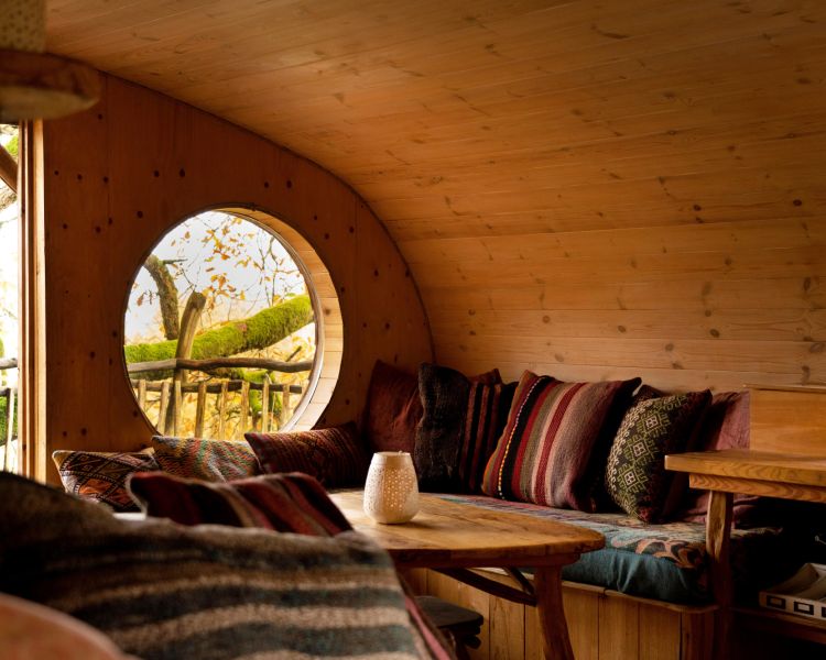 the living area with comfy seating inside a treehouse in the woods in wales