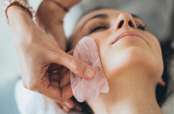 woman having a facial massage with gua sha tool
