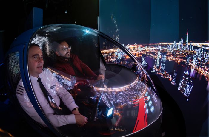 man and pilot in the cockpit of an r22 helicopter flight simulator at luton airport