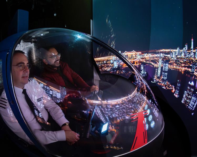 man and pilot in the cockpit of an r22 helicopter flight simulator at luton airport