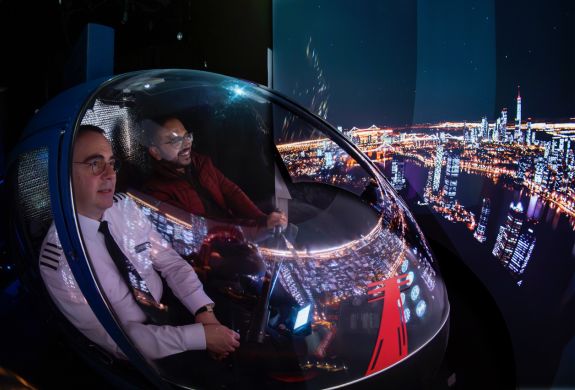 man and pilot in the cockpit of an r22 helicopter flight simulator at luton airport