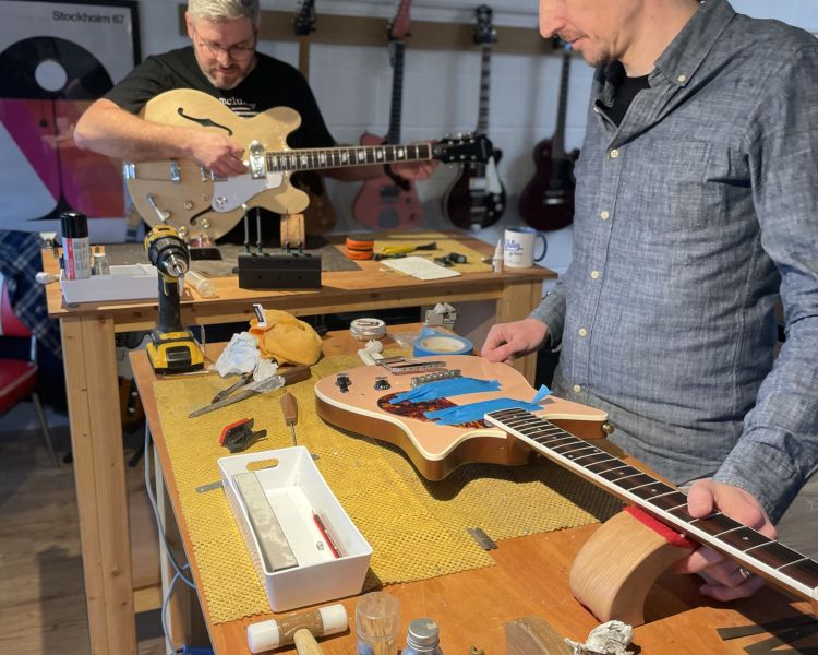 2 men rewiring guitars