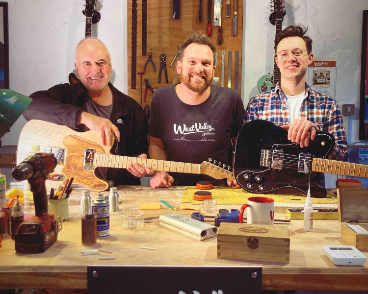 3 men with guitars in a workshop