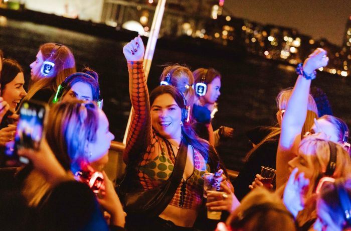 happy party goers on a silent sounds party river cruise on the thames in london