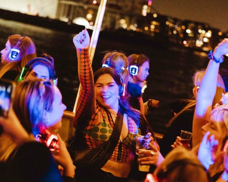 happy party goers on a silent sounds party river cruise on the thames in london