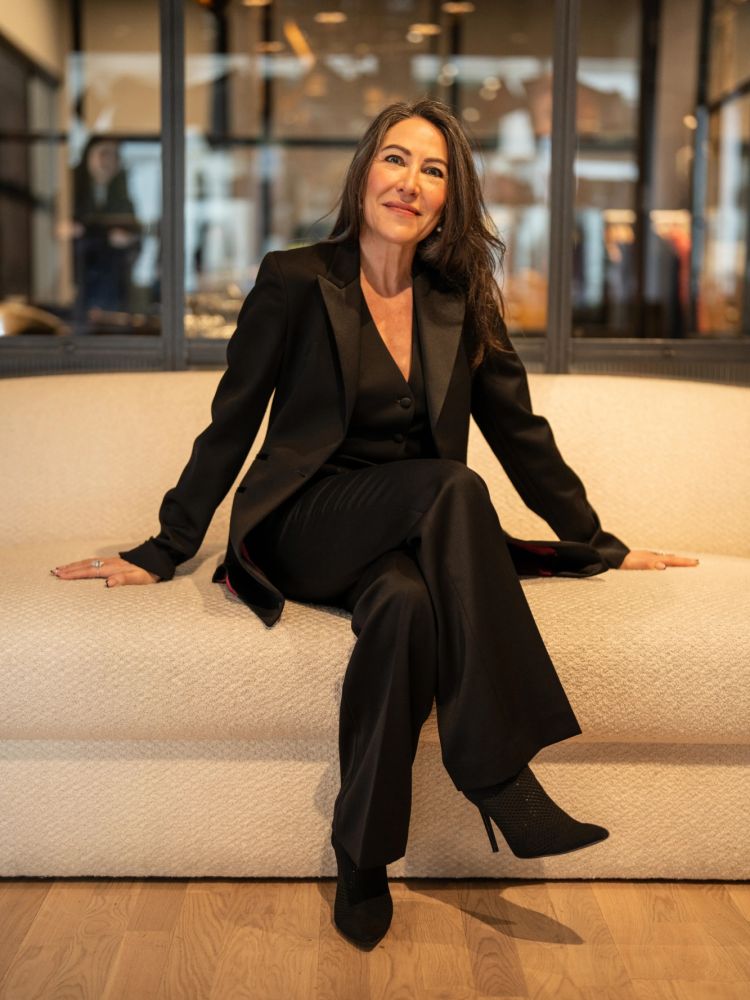 woman sitting wearing a black suit designed an made in savile row london