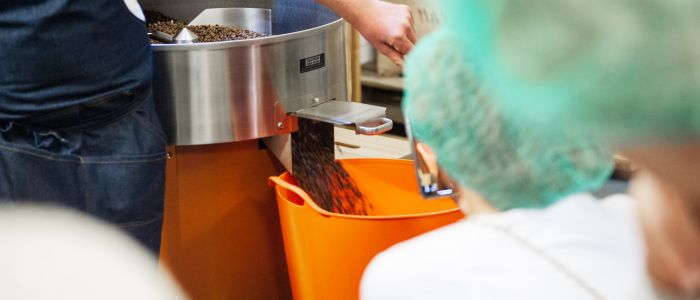 group watching coffee beans being roasted at a how to make coffee workshop