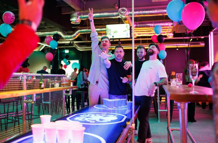 Four men playing beer pong in a bar