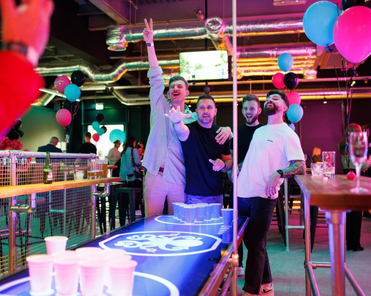 Four men playing beer pong in a bar