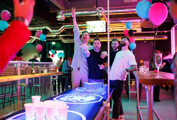 Four men playing beer pong in a bar