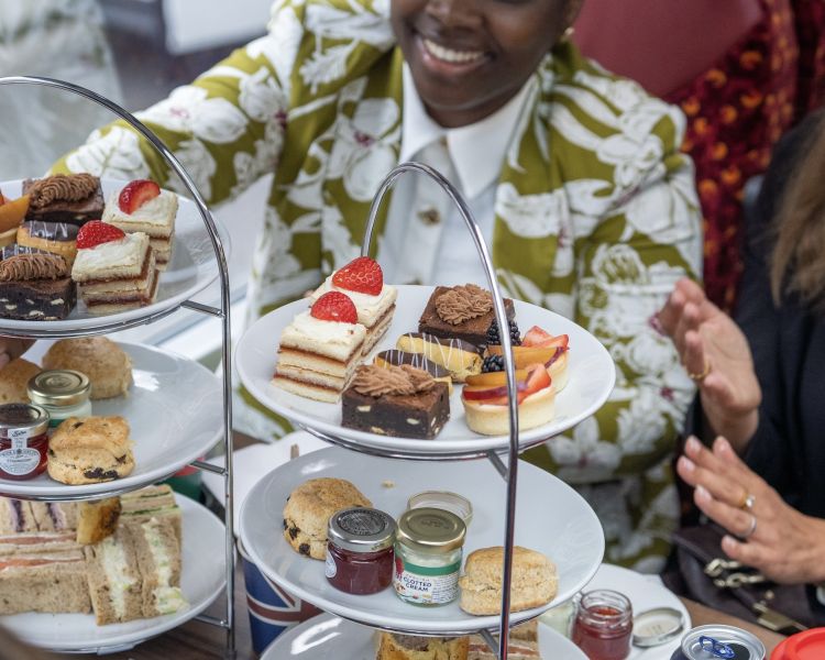 Two ladies eating an afternoon tea on a pg tips london tour bus