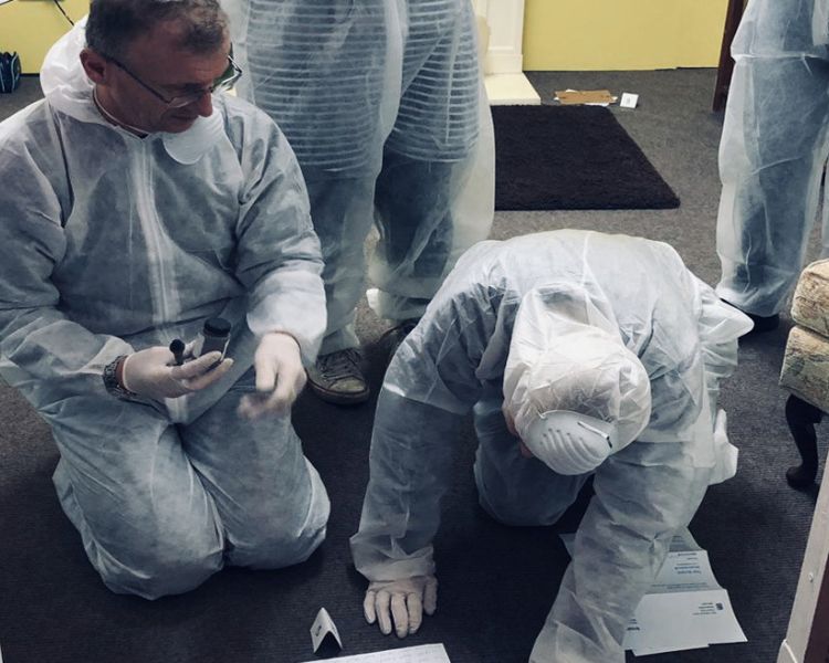 people dressed in white protective suits taking part in a crime scene investigation experience day