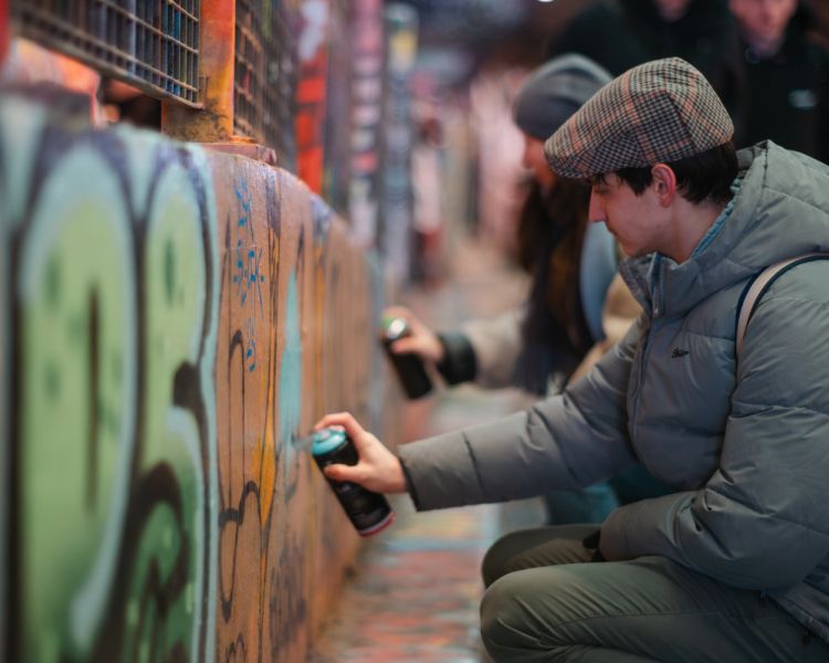 Man spraying paint in graffiti tunnel