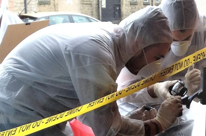 two people dressed in personal protective clothing and face masks on a forensic csi experience day