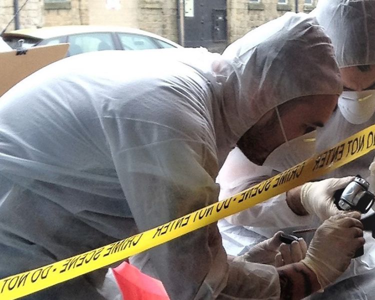 two people dressed in personal protective clothing and face masks on a forensic csi experience day
