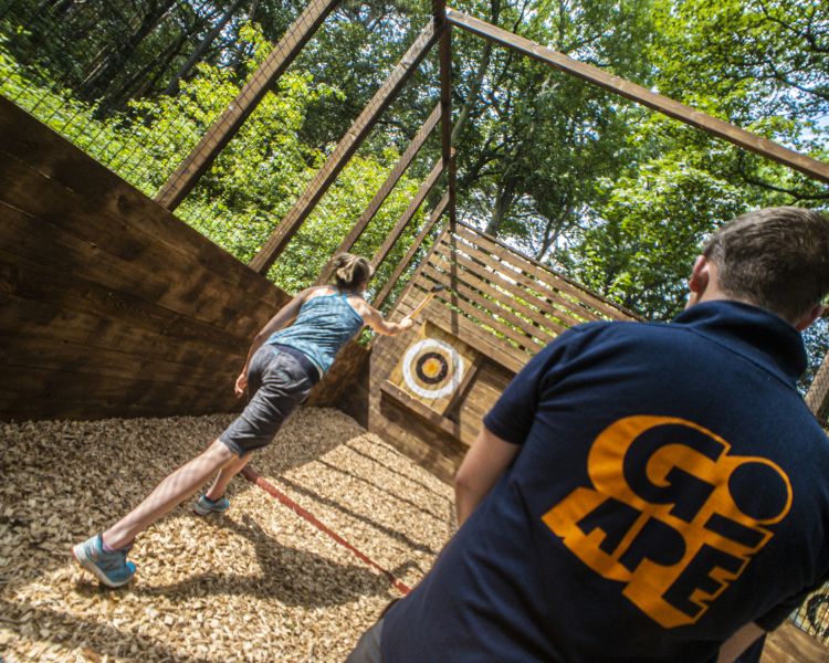instructor watching girl axe throwing at go ape