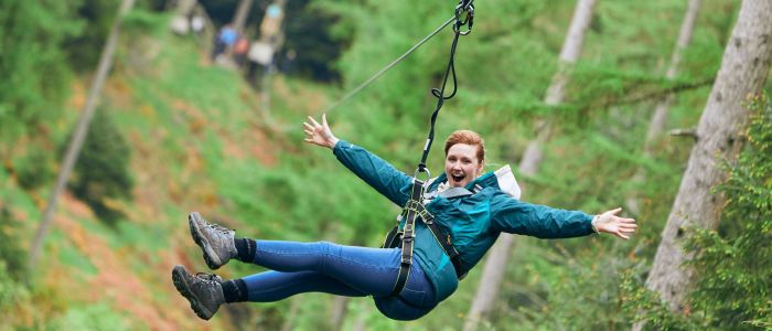 girl with arms outstretched on zip line at go ape zip trekking experience