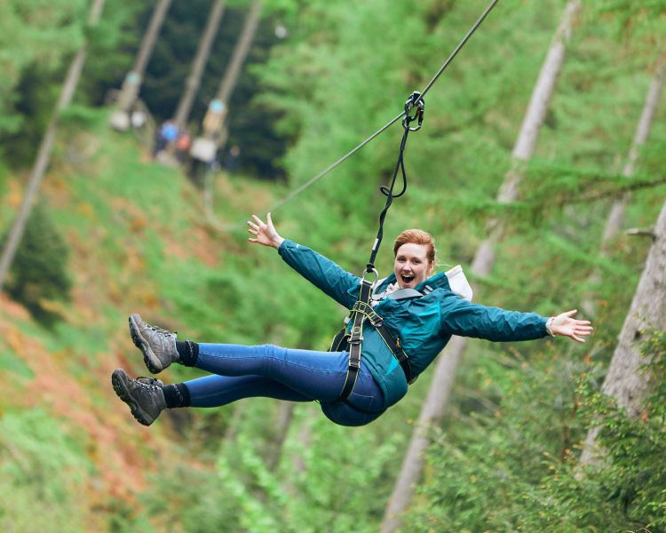 girl with arms outstretched on zip line at go ape zip trekking experience