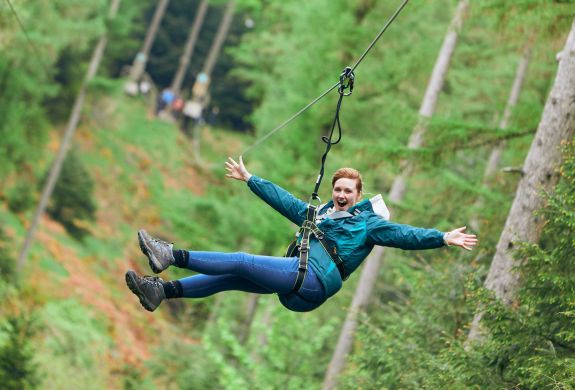 girl with arms outstretched on zip line at go ape zip trekking experience