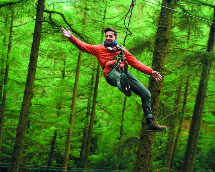 man zip lining through trees at go ape zip trekking adventure