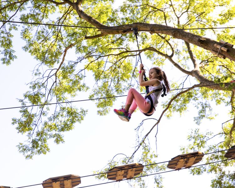 girl on zip wire on the treetop adventure course at go ape