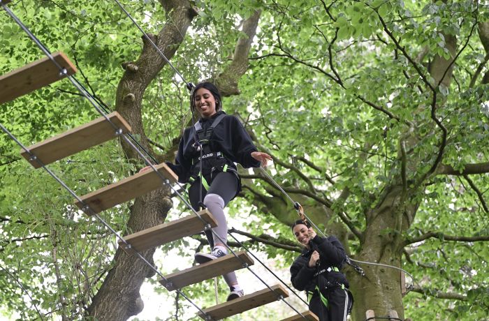 two girls walking the rope bridge on treetop adventure plus course at go ape