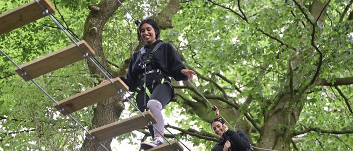 two girls walking the rope bridge on treetop adventure plus course at go ape